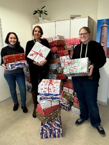Dinara Quarz-Pleuger, Tiffany Wiener (beide ATAMYA) & Christine Diem (Caritas Bochum) bei der Geschenkübergabe für die Aktion "Weihnachten im Schuhkarton".