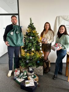 Mike Ehlers vom Kinderheim Herne, Tiffany Wiener & Dinara Quarz-Pleuger (beide ATAMYA) bei der Geschenkübergabe der ATAMYA Weihnachtsaktion.